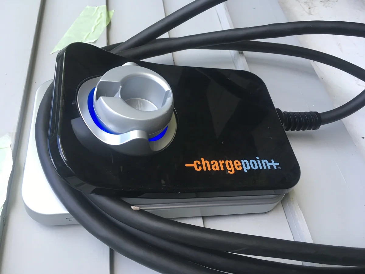 Wall-mounted home EV charger connected outside a house.